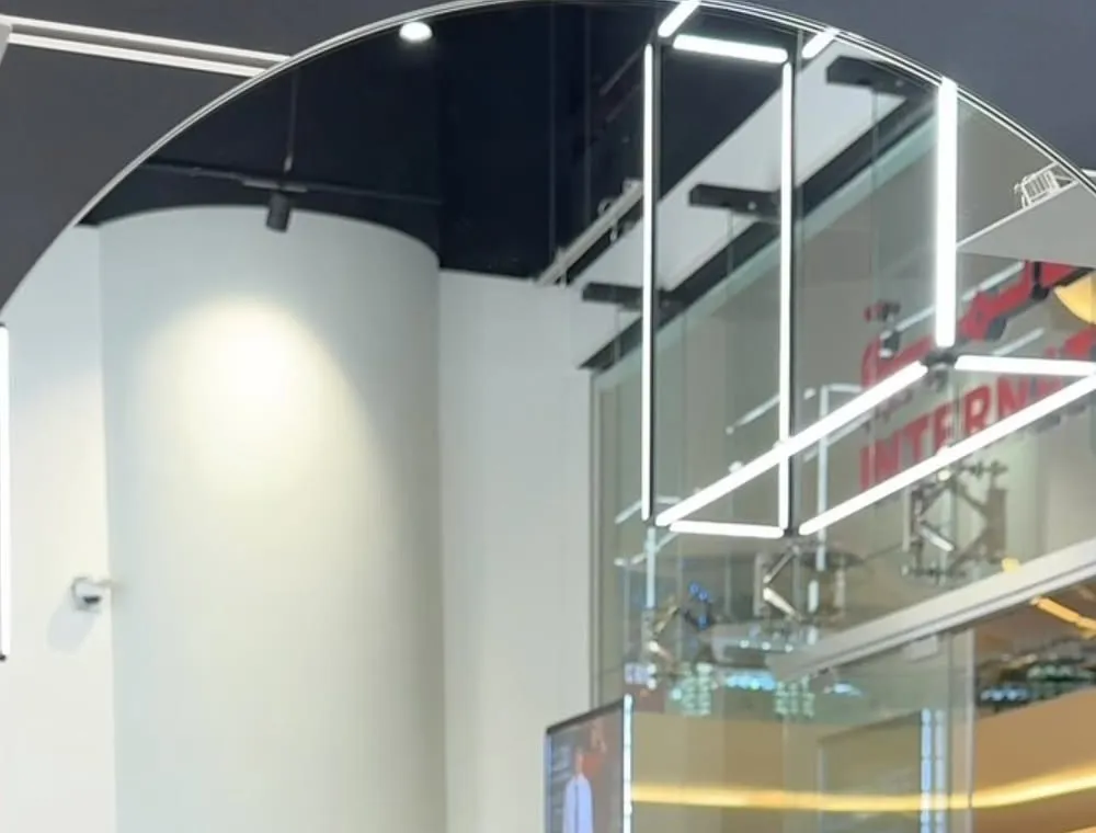 Inside an International Optique store, seen in a round mirror: glass front, light fittings and the mall beyond