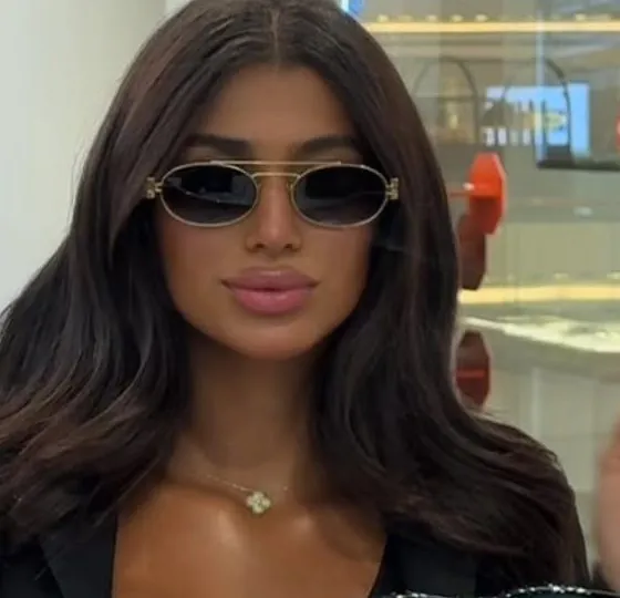 Close-up of slim gold oval sunglasses with a double bridge and dark lenses